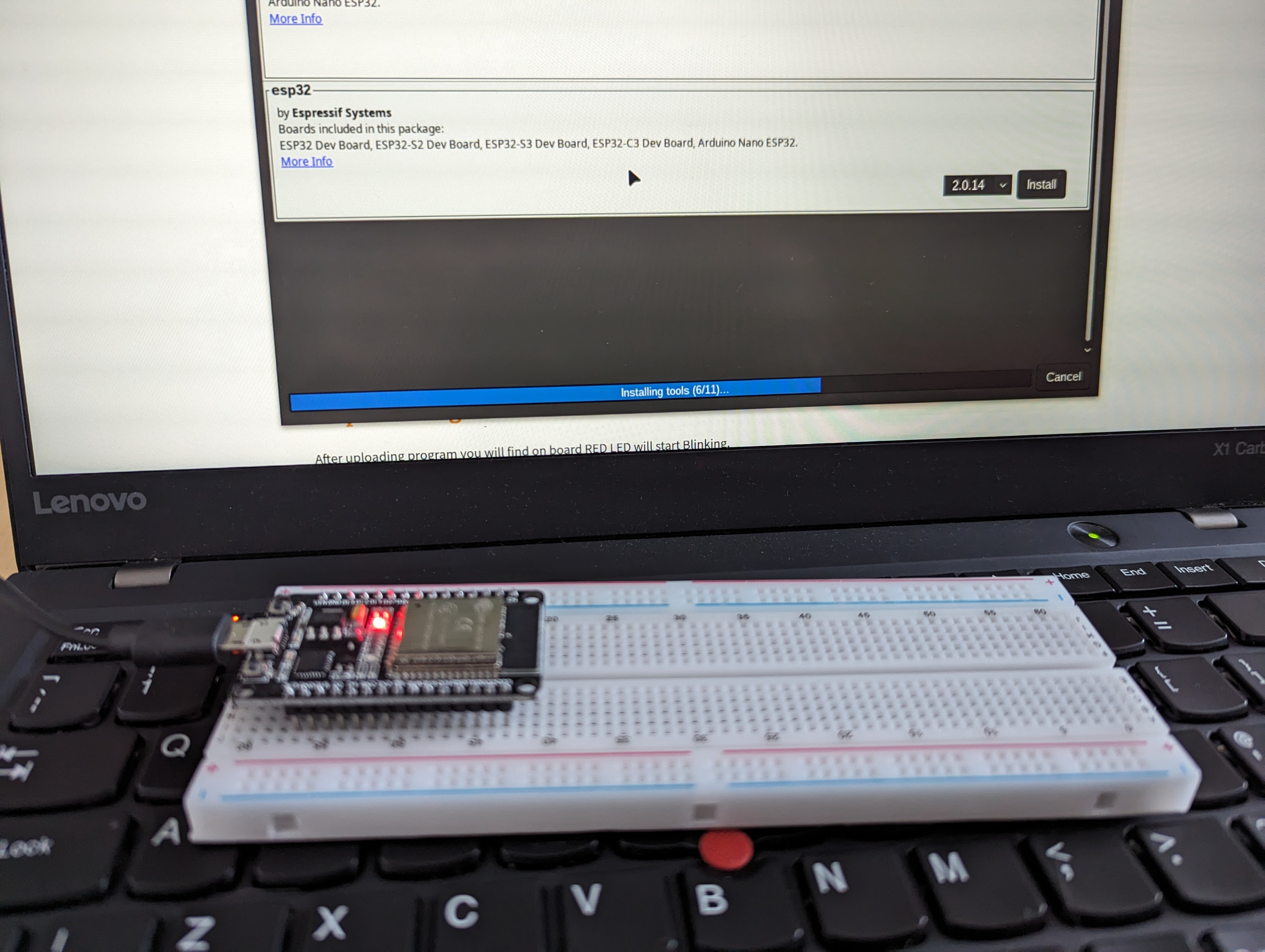 An ESP32 dev board on some breadboard, sat on the keyboard of a laptop. The ESP32 driver installation is occurring in the background.